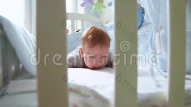 一个小孩在婴儿床上的特写镜头，笑着从婴儿床的格子间侧视。 快乐的童年，幼稚的快乐